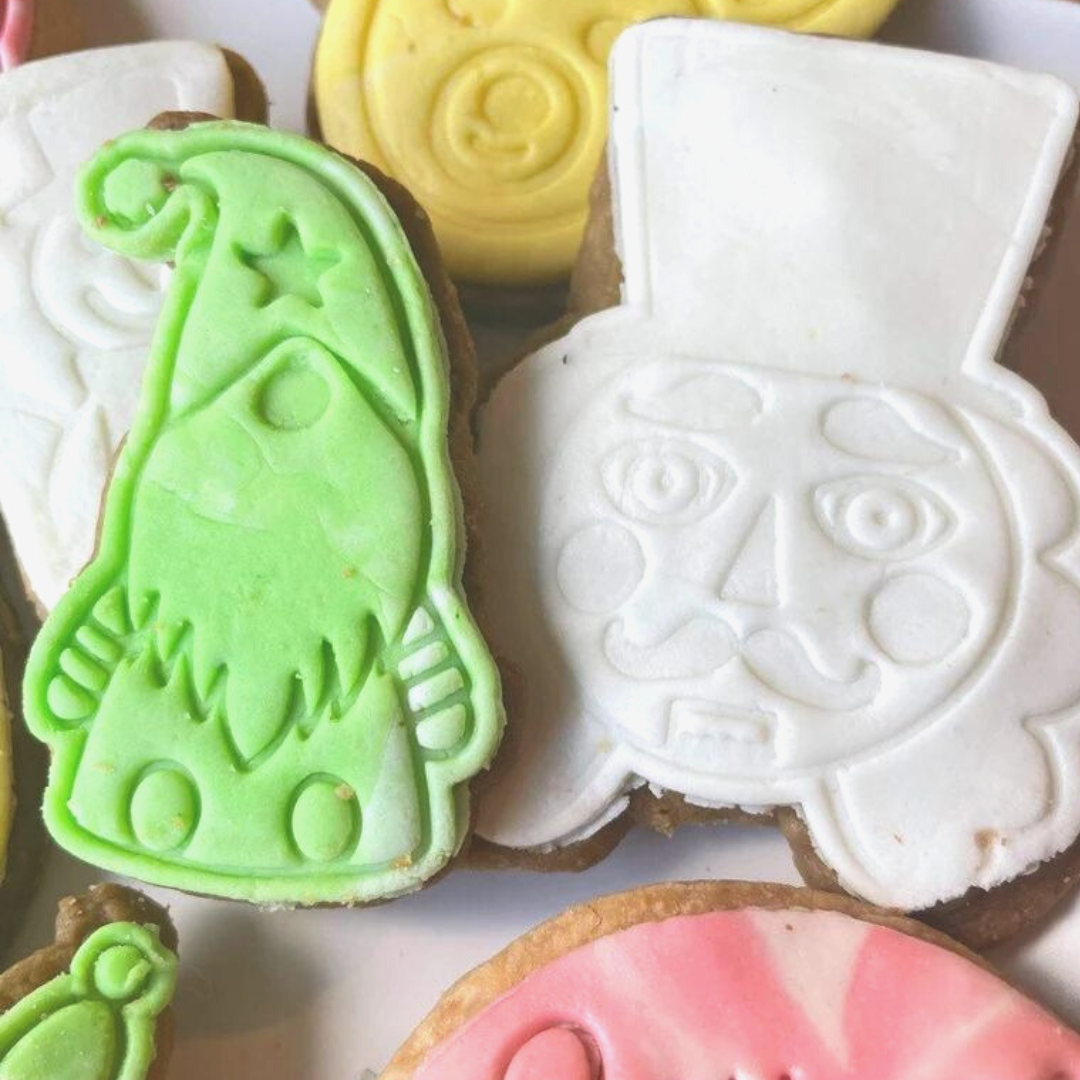 A plate of freshly baked, festive hand-made Christmas cookies, decorated with holiday sprinkles and frosting.